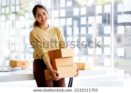 Startup small business entrepreneur of freelance Asian woman using a laptop with box Cheerful success Asian woman her hand lifts up online marketing packaging box and delivery SME idea concept Royalty-Free Stock Photo #2132111703
