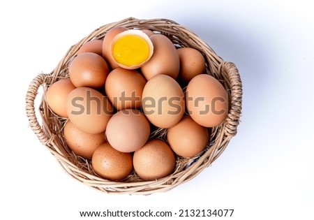 Fresh eggs collected inside wicker basket and one broken, suitable as a food ingredient. Fresh eggs from quality organic farms isolated on white background. Healthy food concept