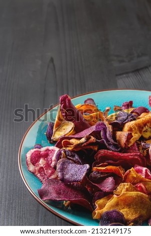 Beet and carrot salty chips in an old blue plate. wood background