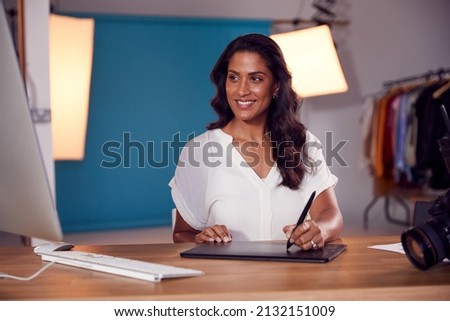 Female Photographer Designer Or Retoucher At Desk Working On Images On Computer In Studio