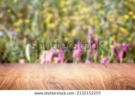 A wooden table and in the background a field with wild flowers can be sensed