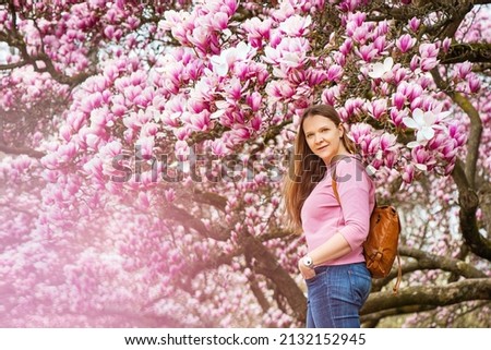  Portrait of beautiful young woman near blooming magnolia tree outdoors 