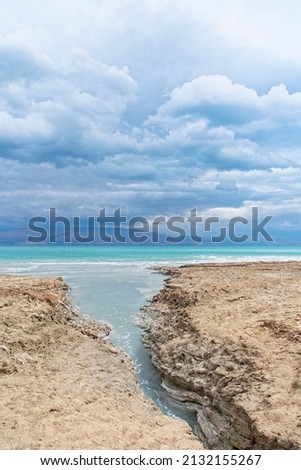 Sinkhole filled with turquoise water, near Dead Sea coastline. Hole formed when underground salt is dissolved by freshwater intrusion, due to continuing sea-level drop. . High quality photo