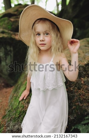 Ukrainian 7 year old girl with white hair like an angel walking in the woods on the rocks.