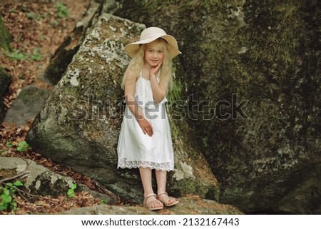 Ukrainian 7 year old girl with white hair like an angel walking in the woods on the rocks.