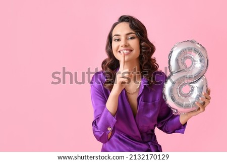 Smiling young woman with balloon in shape of figure 8 on pink background. International Women's Day