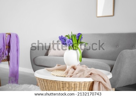 Vase with flowers on table near sofa in room