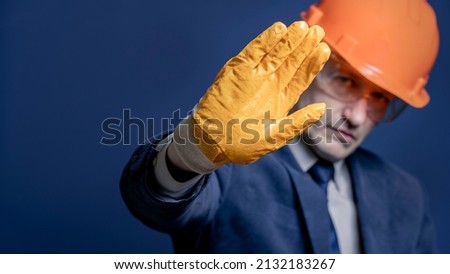 Close up of a businessman or engineer in a construction hard hat making a stop sign with his hand