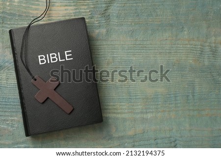 Christian cross and Bible on wooden table, top view. Space for text