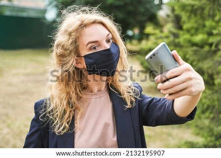 Young woman doing self portrait outside in mask. Park vacation portrait. Blogger selfie video. Travel local. Alone tourist. Happy emotion. Smiling female person. Lifestyle action. Posing
