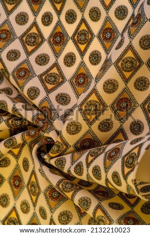 silk fabric in soft beige color with a print of rhombuses, squares and medals. Tell a story and make a statement with traditional design work that has charm and value. Texture background pattern
