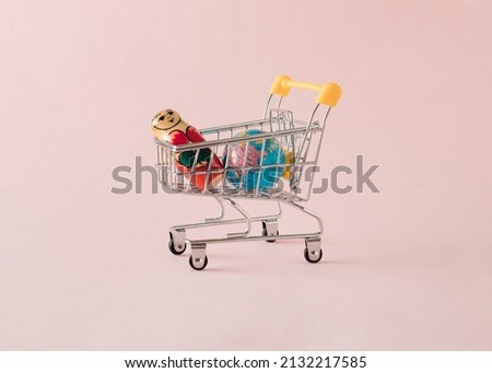 Globe and Russian traditional wooden doll in a supermarket cart. Minimal concept problem planets on light pink backgrounds