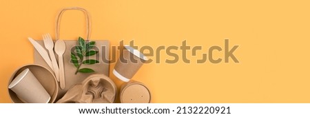 Banner with eco-friendly tableware set. Kraft paper utensils, paper containers and cups, bamboo cutlery on orange background, copy space. Street food paper packaging concept, ethical consumerism Royalty-Free Stock Photo #2132220921