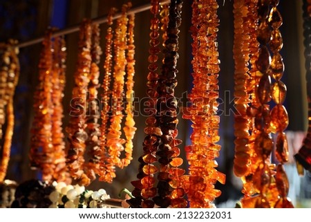 Various amber orange beads made of stones are hanging on the counter. Jewelry