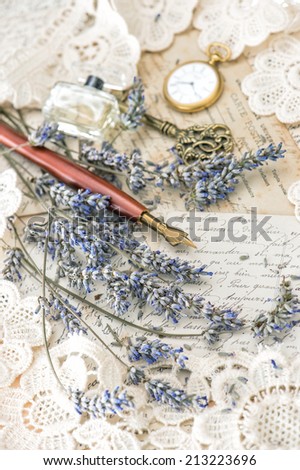 vintage ink pen, key, perfume, pocket clock, lavender flowers and old love letters. retro style toned picture. selective focus
