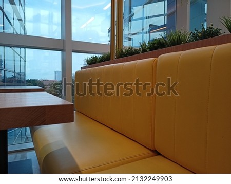A long yellow wooden sofa as interior furniture for a cafe.