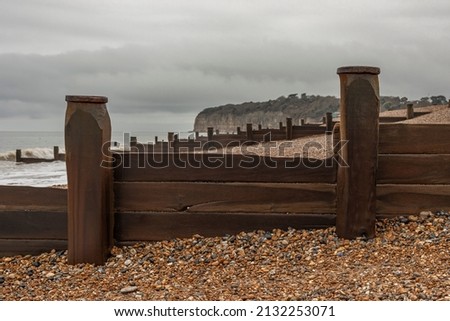 Looking along the shore at the wooden wave breaks on a Sothern UK beach on a stormy day