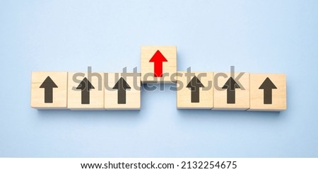 Wooden blocks with arrows with one moving forward and standing out from the crowd. Concept of competitive advantage in business startup. Royalty-Free Stock Photo #2132254675