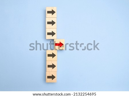 Wooden blocks with arrows with one moving forward and standing out from the crowd. Concept of competitive advantage in business startup. Royalty-Free Stock Photo #2132254695