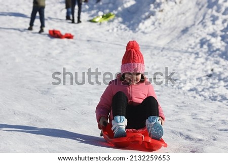 A closeup shot of the Caucasian girl playing in the snow on a sunny day