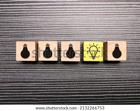 A line of light bulbs icon on wooden cubes. Idea selection concept.