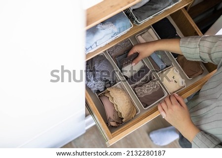 Top view female hands comfortable boxes storage for panties, socks, bras Konmari method storage. Woman neatly putting underwear into organizer container for vertical system cupboard general cleaning Royalty-Free Stock Photo #2132280187