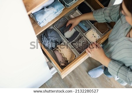 Top view female hands comfortable boxes storage for panties, socks, bras Konmari method storage. Woman neatly putting underwear into organizer container for vertical system cupboard general cleaning