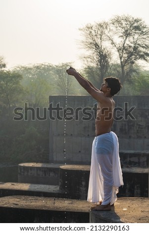 Indian priest praying to Sun, indian priest praying to surya while dropping water in showing respect to god.