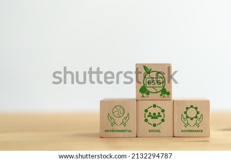 ESG concept of environmental, social and governance. Sustainable corporation development. Hand holds wooden cubes with abbreviation ESG standing with other ESG icons on white background. Copy space. Royalty-Free Stock Photo #2132294787