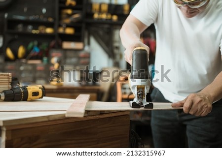 Carpenter cutting wooden with electric jigsaw in workshop, woodworking concept , selective focus Royalty-Free Stock Photo #2132315967