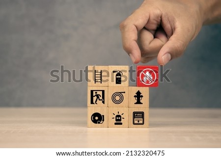 Hand choose cube wooden block stack with fire prevent icon with door exit with fire extinguisher and emergency protection symbol for safety and rescue and fire prevention training.