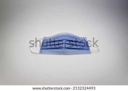 Darker shade of blue colored medical or surgical 3 layer mask on white background