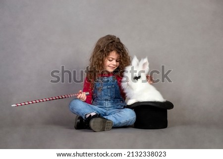 Little girl playing with real rabbit, Bunny in a hat, they make magic