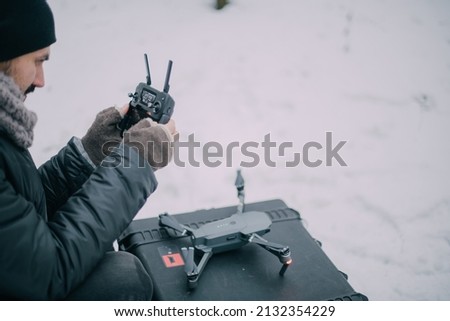 Aerial photography specialist with a copter in his hands on the street in winter. A male aerial drone operator at work on a film set for a movie, commercial or broadcast. Modern photography technology