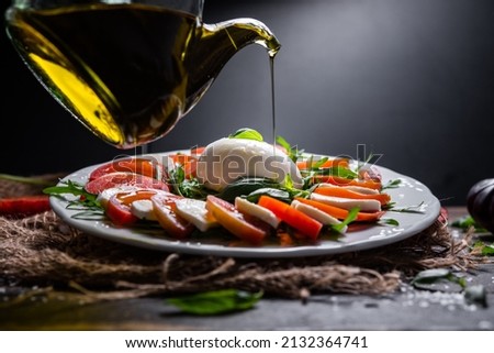 Typical Italian dish of cow or buffalo mozzarella cheese, with arugula, basil, tomato, olive oil, and coarse salt, typical of Caserta and Saleno, Italy. Royalty-Free Stock Photo #2132364741