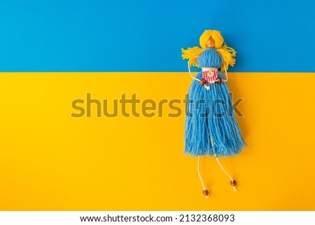 Symbol of Ukrainian nation is a handmade doll knitted from yellow and blue threads. On the paper flag of Ukraine. Stop Putin. Stop war in Ukraine. High quality photo