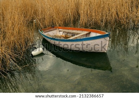 one boat moored near reed grass on Lake Ohrid during a cloudy day Royalty-Free Stock Photo #2132386657