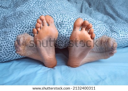 Woman suffering from foot cramps, leg cramps or muscular spasm while sleeping. Feet pain or feet ache at night. Restless legs syndrome Royalty-Free Stock Photo #2132400311
