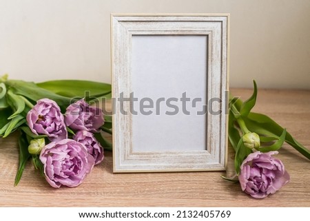 Portrait white picture frame mockup on wooden table. Modern vase with tulips.Scandinavian interior. High quality photo