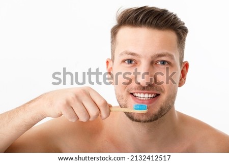The smile of a young man in close-up. A man holds a toothbrush in his hand. The concept of oral care.