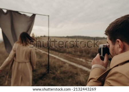man takes pictures of a woman on a gray background