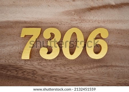 Wooden  numerals 7306 painted in gold on a dark brown and white patterned plank background.