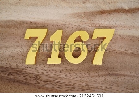 Wooden  numerals 7167 painted in gold on a dark brown and white patterned plank background.
