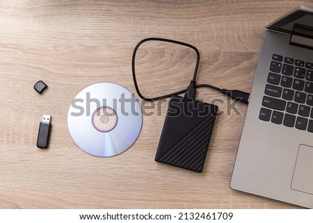 Digital custodians of information. External hard drive, cd and usb flash drive, laptop on a wooden table