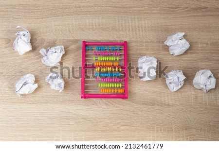 Abacus among crumpled sheets of paper on wooden table. Business concept