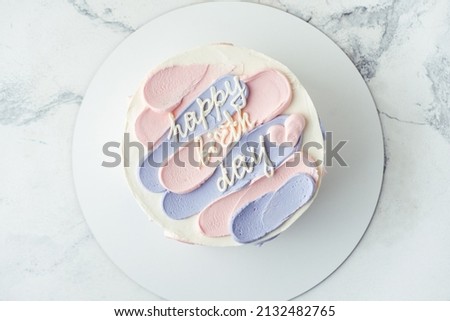 Bento cake with blue and pink cream cheese frosting and Happy birthday text on top. Birthday cake on white background. Asian small cake trend.