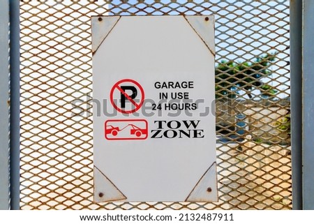 In Malta Sign hanging on a fence gate - GARAGE IN USE 24 HOURS - TOW ZONE