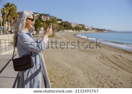 Urban lady taking pictures of beautiful coastline