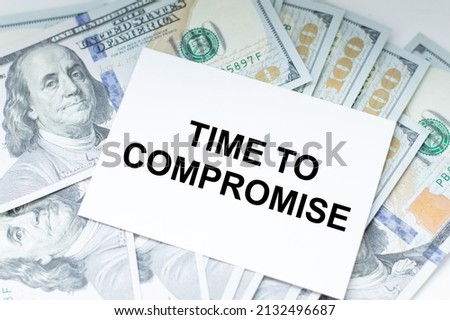 On the business card the text of Time to compromise against the backdrop of dollar banknotes