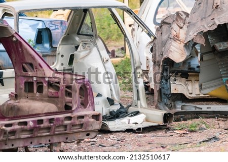 Metal broken cars body parts abandoned outdoors. Car dump, wreck at a junkyard ready for recycling. Atmospheric weathered auto junk Royalty-Free Stock Photo #2132510617
